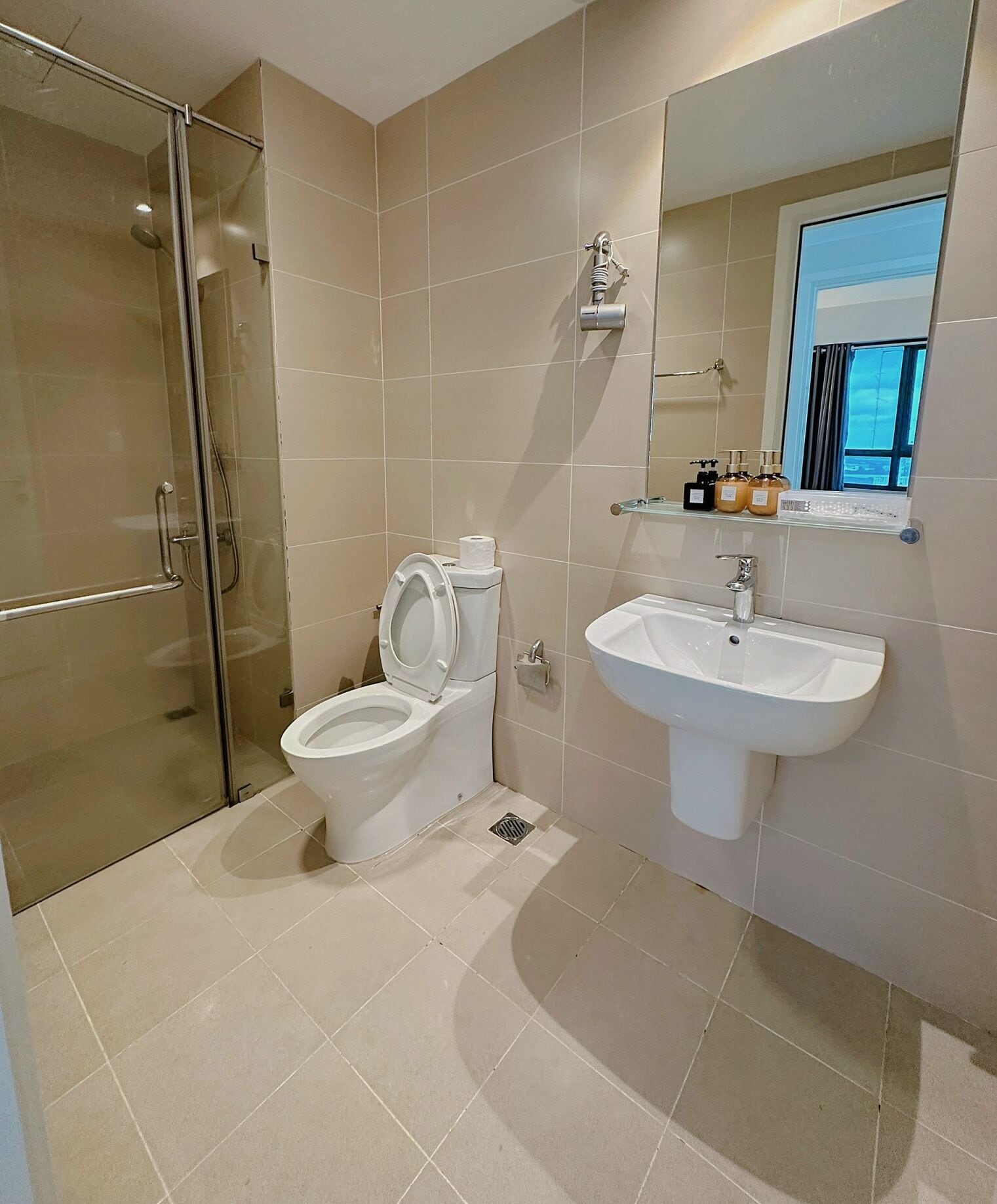Un baño moderno con cabina de ducha de vidrio, inodoro y lavabo con espejo.