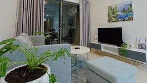 Un salon moderne avec un canapé, une table basse, un téléviseur et une plante en pot.