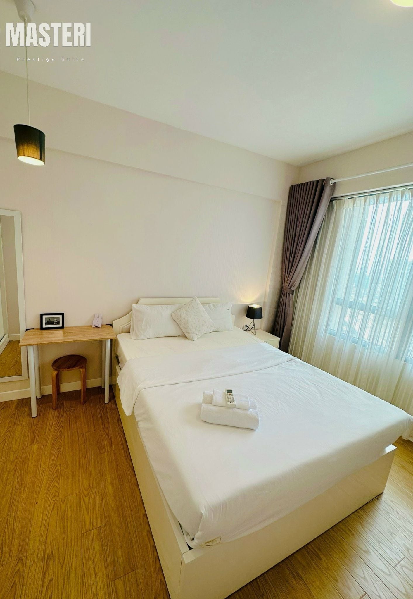 Ein Hotelzimmer mit einem großen Bett, einem Schreibtisch, einem Stuhl, einem Spiegel und einem Fenster mit Vorhängen.