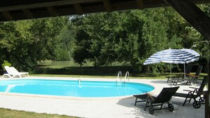 A swimming pool with lounge chairs and an umbrella, surrounded by trees. - Gîte en Zone Natura 2000, à 11 kms de Beauval. Calme et Cadr Idéal en Famille (Meusnes)