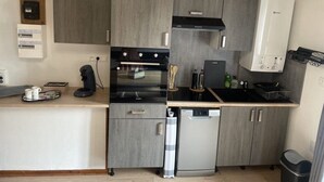 A compact kitchen with grey cabinetry, a built-in oven, a dishwasher, and a coffee machine. - Superbe Appartement Neuf Face au Château - 2 ch / 5 Pers - Netflix Canal+ - Wifi (Sedan)