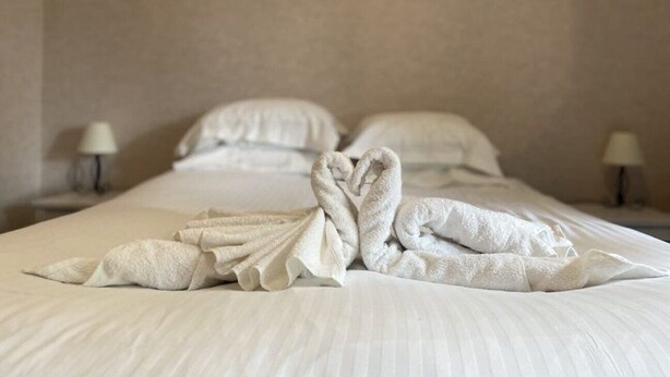 A neatly made bed with white linens and a heart-shaped towel arrangement. - Superbe Appartement Neuf Face au Château - 2 ch / 5 Pers - Netflix Canal+ - Wifi (Sedan)