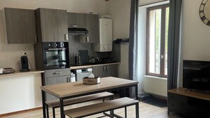 A modern kitchen with wooden beams, a dining table, and a sofa. - Superbe Appartement Neuf Face au Château - 2 ch / 5 Pers - Netflix Canal+ - Wifi (Sedan)