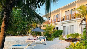 A beachfront property with a pool area, lounge chairs, and a covered seating area. - The Sunset Villa (Dhiffushi)