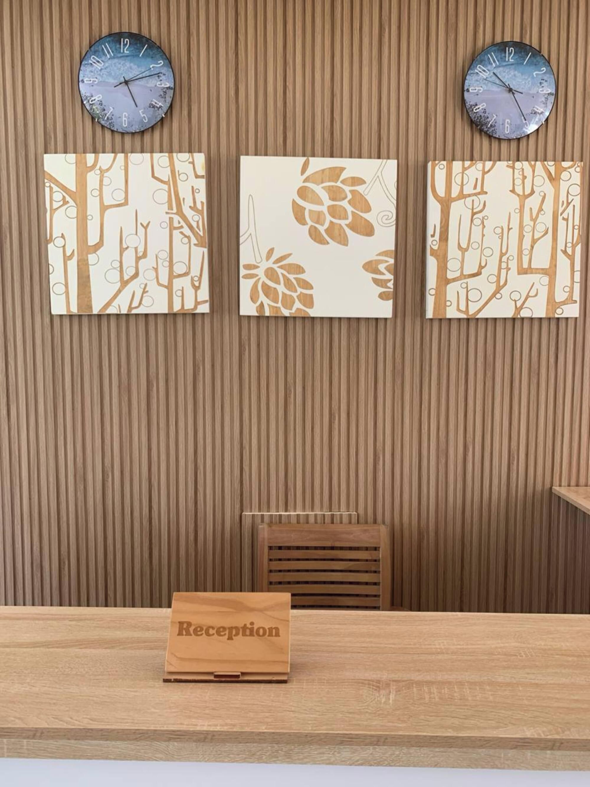 A reception desk with a wooden reception counter and a sign labeled "Reception". Above the desk, there are three wall-mounted clocks.