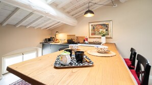 Een eetgedeelte met een houten tafel, een dienblad met kopjes en een theepot, en een schilderij aan de muur.