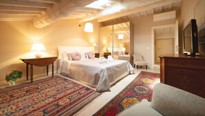 Een slaapkamer met een groot bed, een houten plafond, een spiegel, een televisie en een kamerbreed tapijt met een patroon.