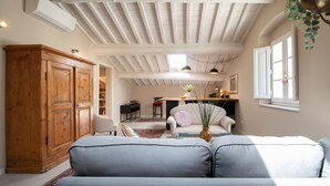 Een gezellige woonkamer met een hoge plafond, houten kasten, een bank en een eethoek met een tafel en stoelen.