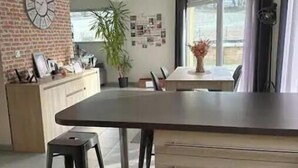 Une cuisine moderne dotée d’un îlot central, de luminaires suspendus et d’un mur d’accent en briques.