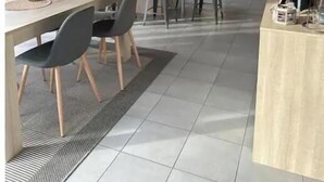 Une cuisine moderne dotée d’un îlot central, de luminaires suspendus et d’un coin repas avec une table et des chaises.