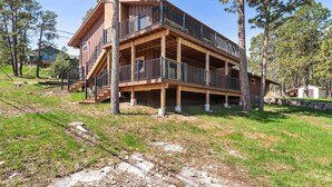 A multi-story wooden cabin with a balcony on each floor, surrounded by trees. - Pinedale Cabin Getaway (Rapid City)