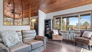 A spacious living room with a wooden ceiling, a large window with a view, and a cozy seating area with a sofa and armchairs. - Pinedale Cabin Getaway (Rapid City)