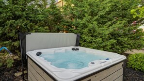 A hot tub in an outdoor setting with a wooden frame, surrounded by greenery. - Beach Daze|Beachfront Bungalow+HotTub+Beach Access (Sea Bright)