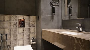 A modern bathroom with a marble sink, a toilet, and a shower.