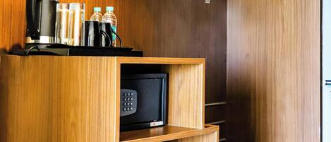 Una kitchenette compacta con microondas, cafetera y perchero.
