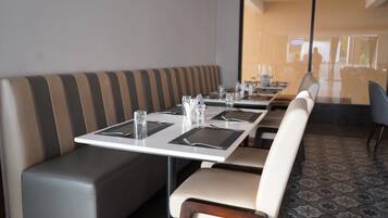 Un comedor con una mesa larga dispuesta para cuatro, un banco acolchado y un suelo estampado.