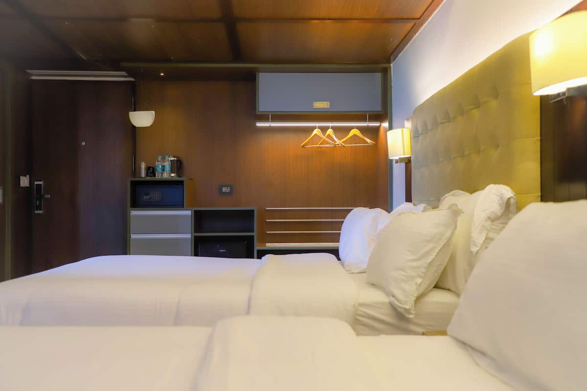 A hotel room with a large bed, a TV, a minibar, and a wooden panel wall.