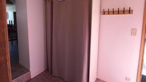 Habitació amb sostre de fusta, una porta tancada amb cortina i un penjador fixat a la paret.