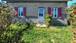 Una casa de dos pisos amb teulada inclinada, una xemeneia i un petit porxo davant.