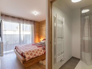 Un dormitorio con cama, radiador y ventana con cortinas.