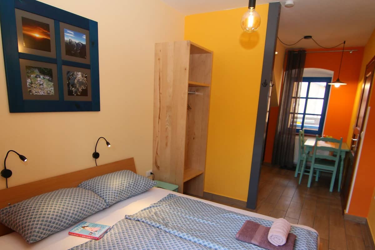 Ein Schlafzimmer mit einem Bett, Nachttischlampen, einem an der Wand befestigten Foto und einem Holzschrank.