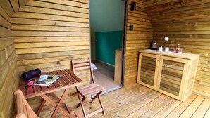 A wooden cabin with a dining area, a small kitchenette, and a bathroom visible through an open door. - Glamping Virje (Bovec)