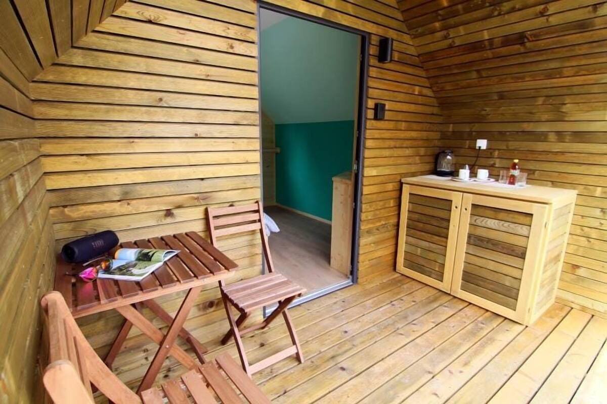 Eine Holzhütte mit Essbereich, einer kleinen Küchenzeile und einem sichtbaren Badezimmer durch eine offene Tür.