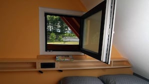 A bedroom with a window, a bed, and a shelf with books. - Glamping Virje (Bovec)