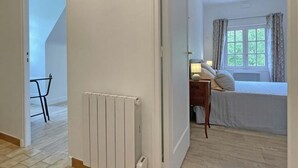 A bedroom with a bed, a nightstand, a window with curtains, and a radiator. - Spacious house for 15 people with garden and pets allowed (Longny-au-Perche)