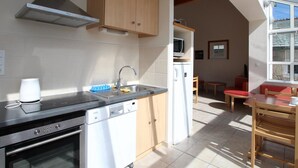 A modern kitchen with a dishwasher, stove, and microwave. There is a dining area with a table and chairs.