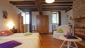 Un dormitorio acogedor con una cama grande, una silla, una mesita y un armario.