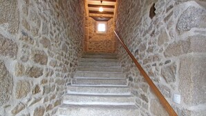 Una escalera de piedra con barandilla de madera que lleva a una pequeña ventana en la parte superior.