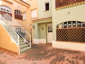 A multi-story building with a staircase, a door with a metal gate, and a tiled courtyard. - Beachfront Apartment with Terrace in Empuriabrava (Ampuriabrava)