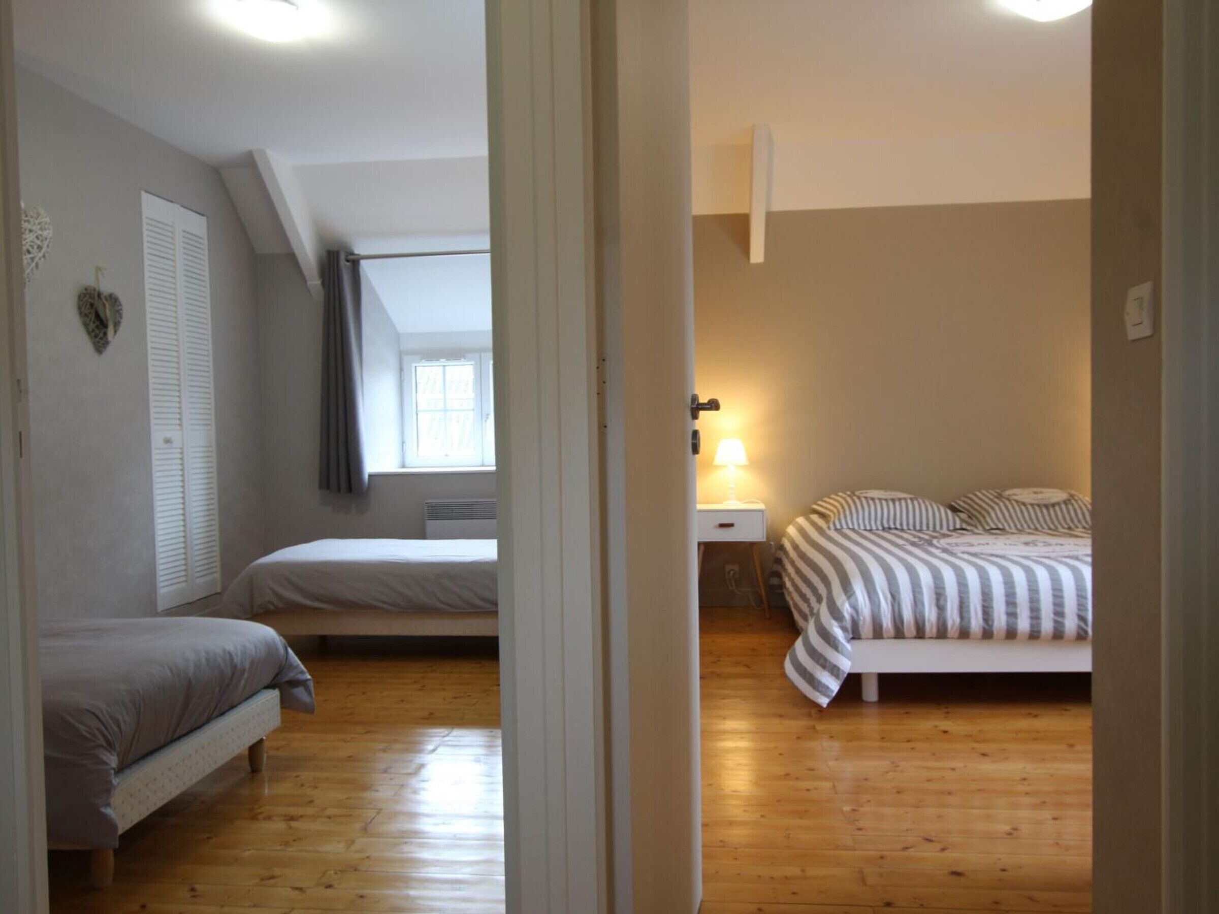 A bedroom with two beds, a window, and a bedside lamp.