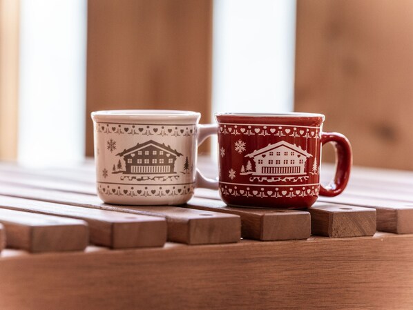 Dos tazas de cerámica con diseño de casa, sobre una superficie de madera.