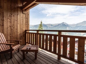 Una terraza de madera con un banco y una mesa, con vistas a un paisaje montañoso.