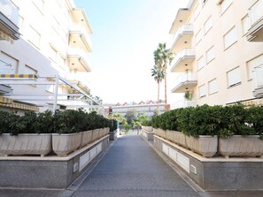 Un chemin bordé de bâtiments à deux étages dotés de balcons, qui mène à un bâtiment surmonté d’un toit rouge.