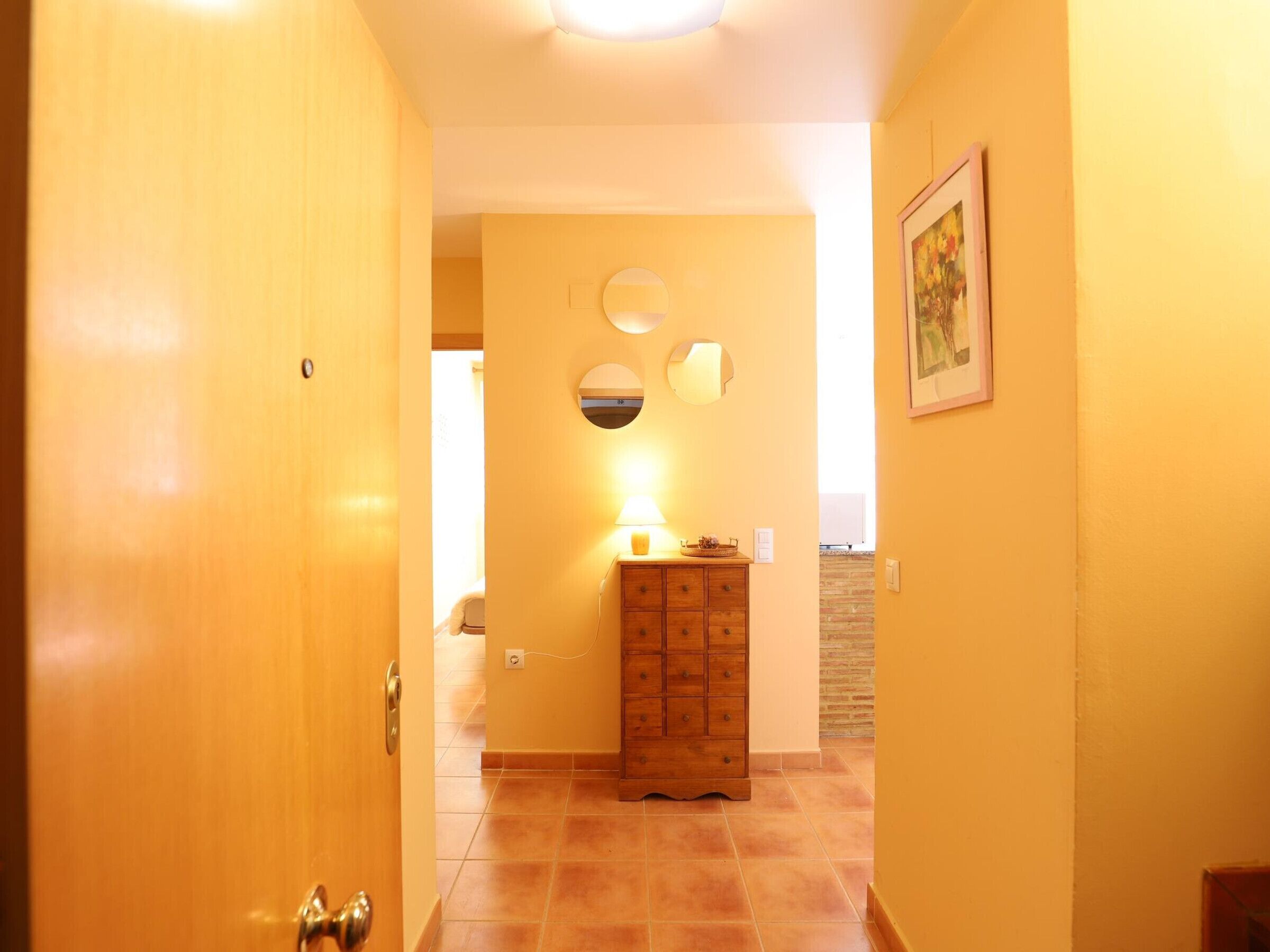 Un couloir avec une porte en bois, une armoire en bois et un miroir fixé au mur.