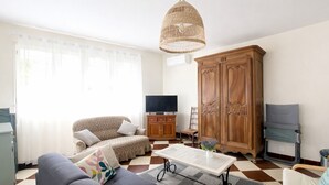 Een woonkamer met een bank, een salontafel, een televisie, een kast en een garderobe.