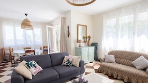 Een woonkamer met een bank, een bijzettafeltje en een eethoek met stoelen en een tafel.