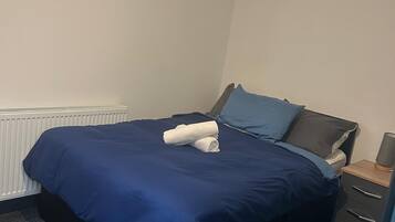 A bedroom with a bed, a nightstand, and a radiator.
