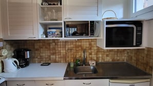 A compact kitchen with white cabinets, a microwave, a coffee maker, and a sink. - 2-Room Apartment in Châtel - 5 People (Châtel)