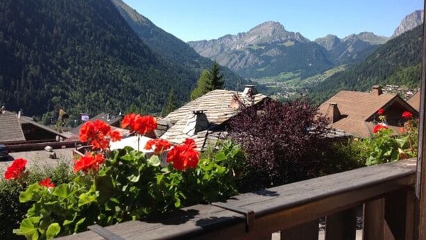 A mountainous village with traditional houses, a wooden deck, and vibrant red flowers. - 2-Room Apartment in Châtel - 5 People (Châtel)