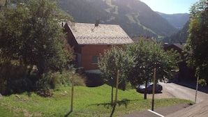 A rural house with a sloped roof, surrounded by greenery and mountains in the background. - 2-Room Apartment in Châtel - 5 People (Châtel)