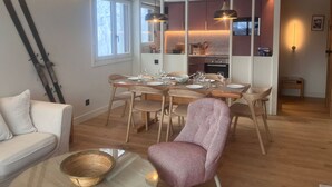 A modern living room with a dining area, wooden flooring, and a kitchen in the background. - 4-room apartment, 8 people, parking, ski slopes (Saint-Gervais-les-Bains)