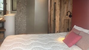 A bedroom with a bed, a wooden wardrobe, a mirror, and a bathroom with a sink. - 4-room apartment, 8 people, parking, ski slopes (Saint-Gervais-les-Bains)