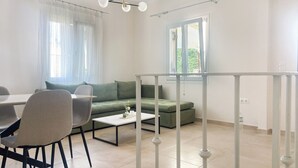 A modern living room with a dining area, green sofa, and a white railing. - Nonna's Hill House (Corfu)