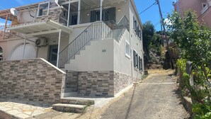 A two-story building with a staircase leading to a balcony. - Nonna's Hill House (Corfu)