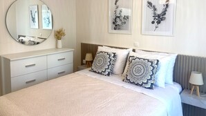 A bedroom with a bed, bedside tables, a mirror, and wall art. - Nonna's Hill House (Corfu)
