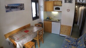 A compact kitchen with a dining table, wooden cabinets, a microwave, and a small refrigerator. - Studio for 4 with balcony, pets allowed and parking (Châtel)